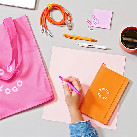 An office desk with pink and orange office supplies customized with your company's logo