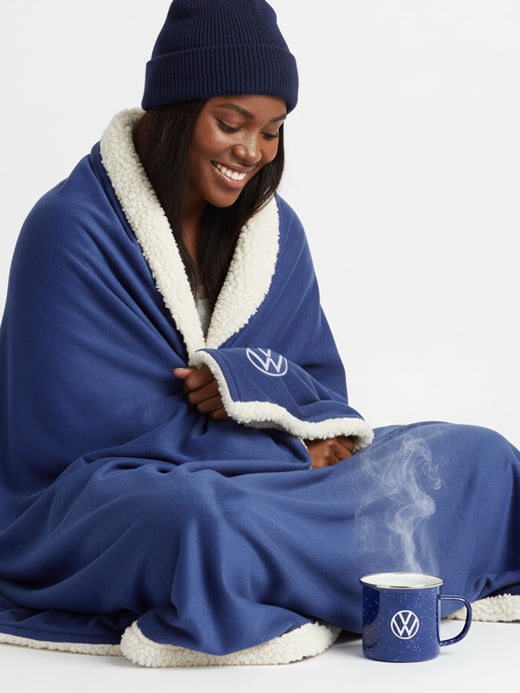 A lady sitting with VW throw blanket wrapped around herself.