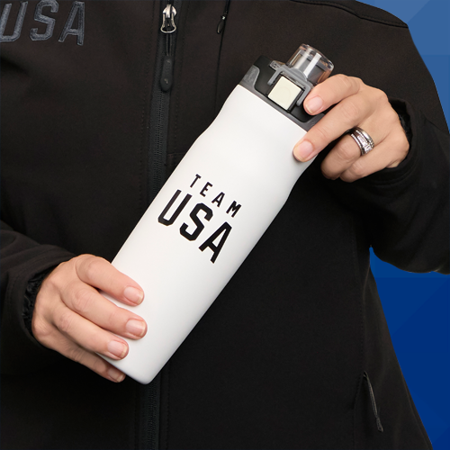 A person in a Team USA jacket holding a water tumbler with the Team USA logo