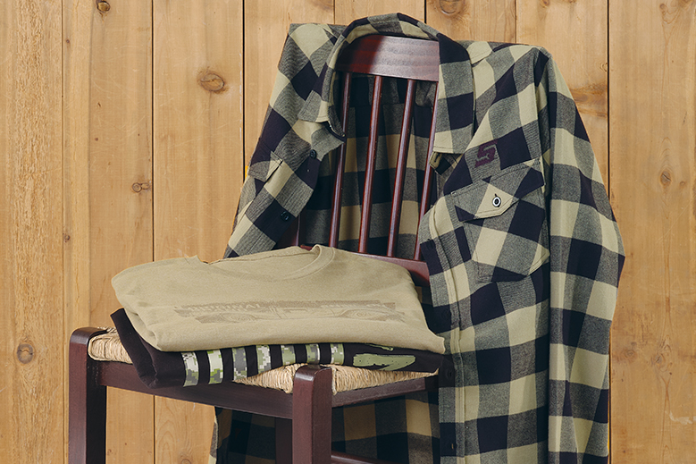 Two folded graphic tees on chair with buffalo print button-up shirt on chair back