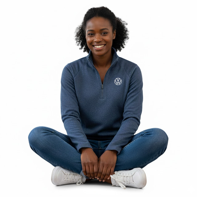 a woman sitting wearing a VW quarter zip performance top