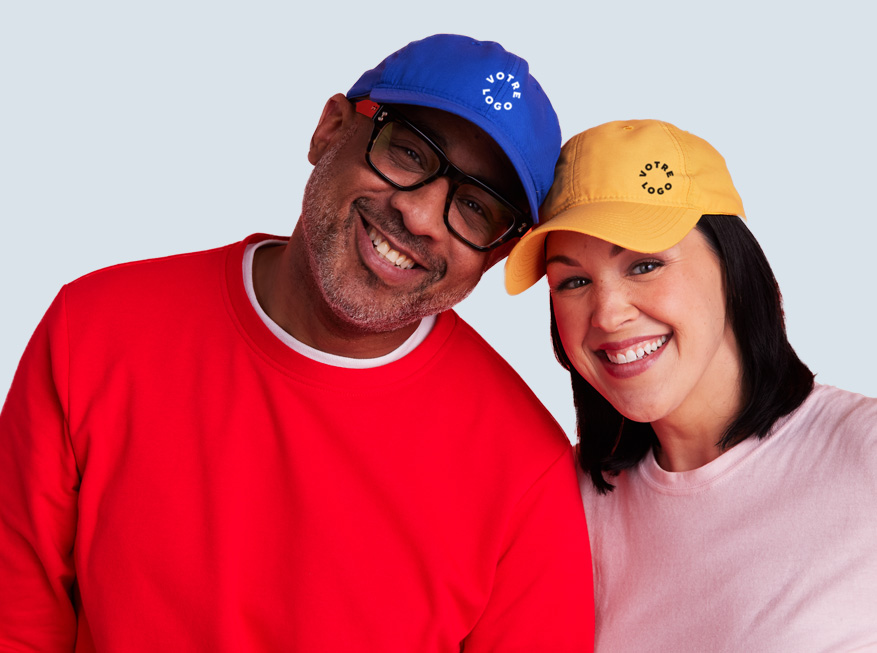 A man and woman wearing blue and yellow custom logo baseball caps, representing the headwear collection