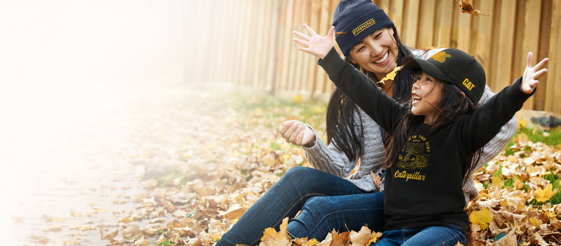 Woman and child playing in fall leaves with Cat apparel and hats