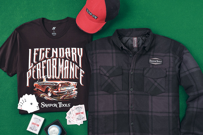 Cap, folded graphic tee, subtle plaid jacket, and playing cards on green felt background